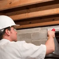 Termite inspection technician checking a basement wall and framing for termite activity in Grand Rapids, MI